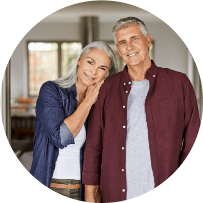 A smiling older couple embracing in a home environment.