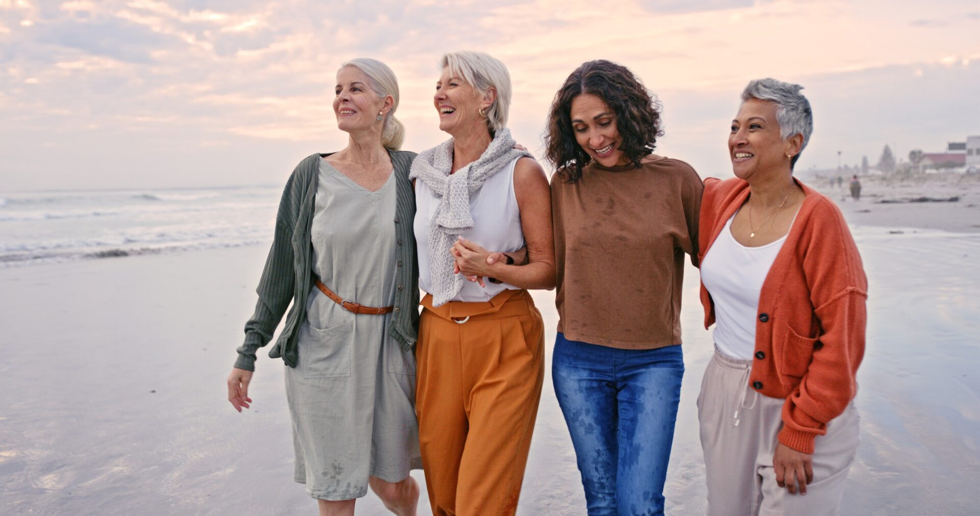 Beach, friends and vacation with a senior woman group walking on the sand by the sea or ocean. Nature, water and friendship with diversity and mature females laughing at sunset in her retirement